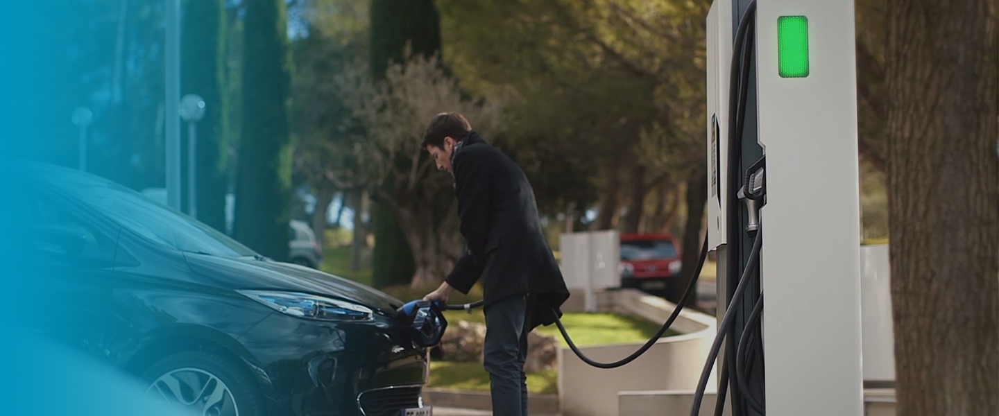 Un homme rechargeant voiture électrique sur borne électrique alizé