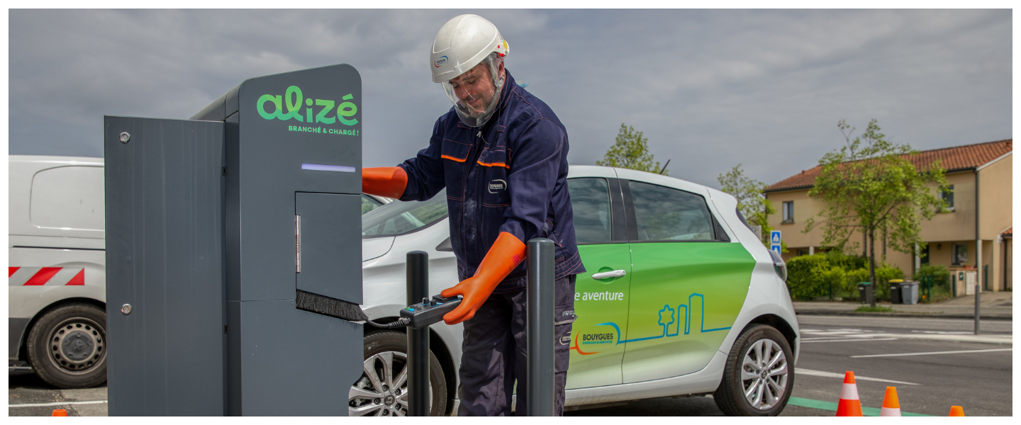 Un homme rechargeant voiture électrique sur borne électrique alizé